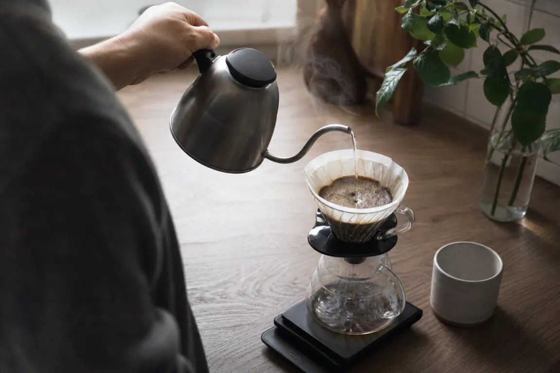 Kägelformad kaffebrytare med pappersfilter och kaffe som droppar ner i en kanna