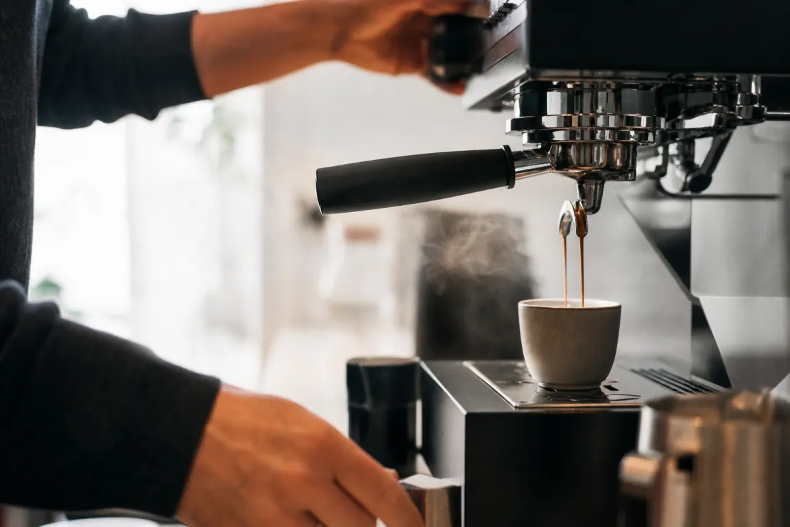 Nymalet kaffe till espresso i en doseringskopp bredvid kvarnen