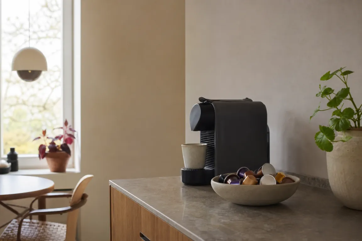 Olika kaffekapslar uppradade bredvid en kapselmaskin
