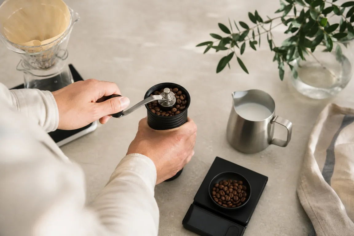 Elektrisk kaffekvarn med bönor bredvid på köksbänken